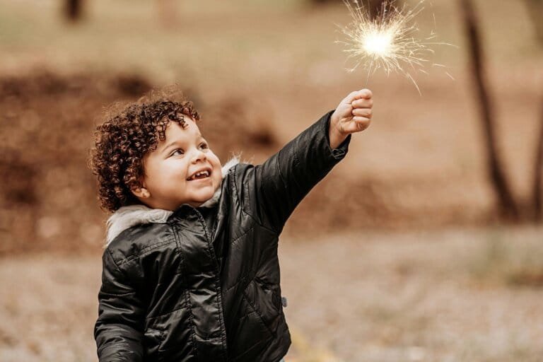 A joyful child holding a glowing sparkler, symbolizing imagination, creativity, and the power of discovering their spark in life.