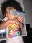 submitted image of a very happy little 2 year old girl. She is happily hugging her copy of Daisy the Deer's Brave Thank You Place, with a beaming smile and a radiant face half hidden by her new treasure.